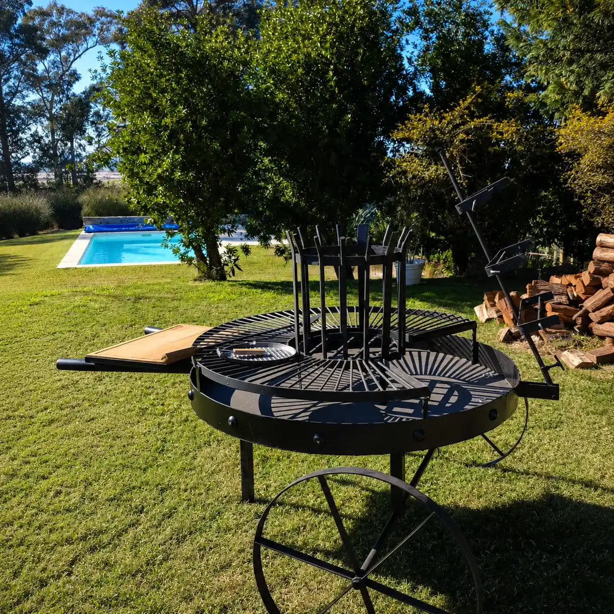 Fogón Criollo 120 junto a una piscina, con la leña apilada al costado