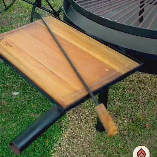 Video del Fogón Criollo 90 de hierro con parrilla, ruedas y tabla de madera, en un jardín