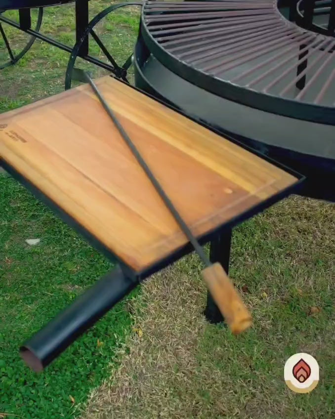 Video del Fogón Criollo 90 de hierro con parrilla, ruedas y tabla de madera, en un jardín