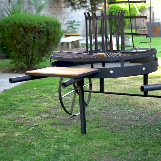 Video del Fogón Criollo 120 de hierro con parrilla, plancha, ruedas y tabla de madera, en un jardín