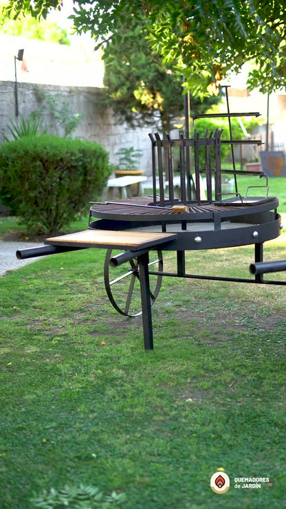 Video del Fogón Criollo 120 de hierro con parrilla, plancha, ruedas y tabla de madera, en un jardín
