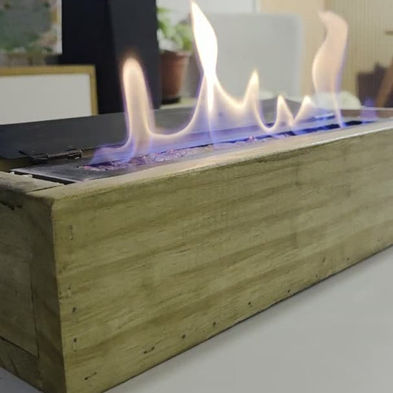 Video de la estufa decorativa de bioetanol 25 cm encendida, con cajón de madera, sobre una mesa